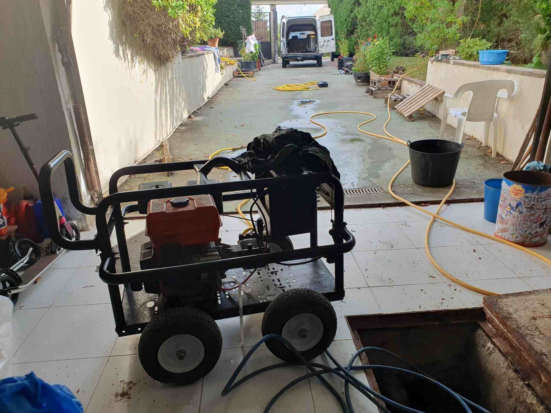 Una hidrolavadora con estructura negra y motor rojo está colocada sobre una entrada de concreto.