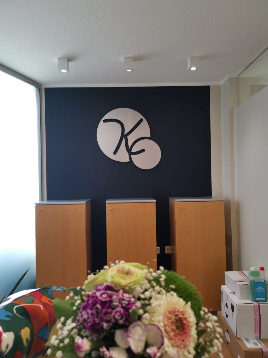 Vor einer Wand steht ein Blumenstrauß mit dem Buchstaben K darauf