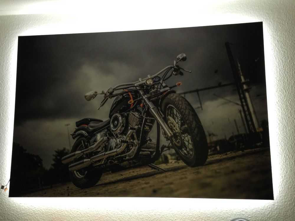 Ein Bild von einem Motorrad an einer Wand mit einem Licht dahinter.