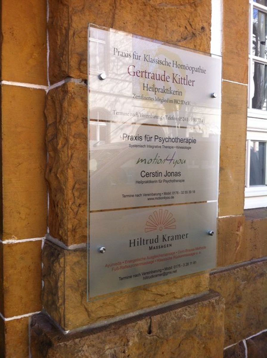 Auf einem Schild an der Seite eines Gebäudes steht der Name einer Person.