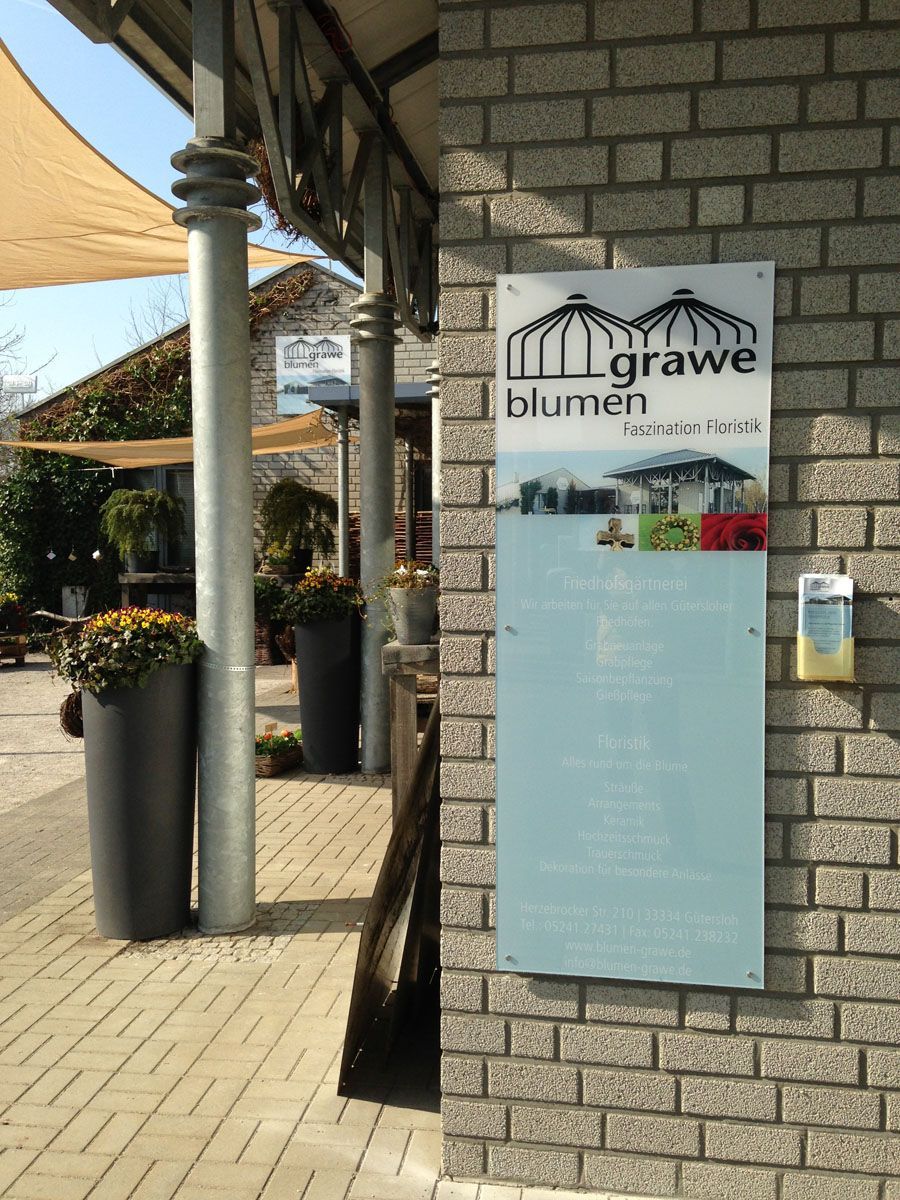 Ein Schild an einer Backsteinmauer sagt Grawe Blumen