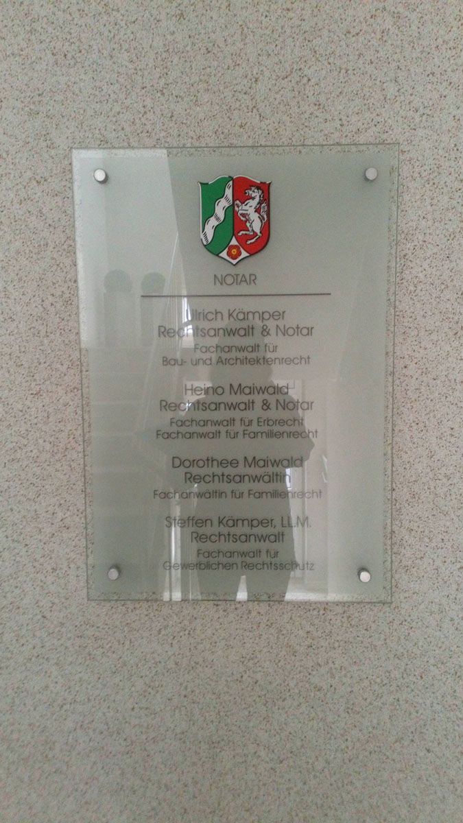 An einer Wand hängt ein Glasschild mit einem Wappen.