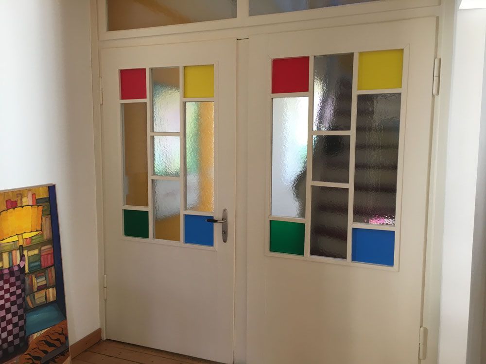 Ein Flur mit Buntglastüren und einem Gemälde an der Wand.