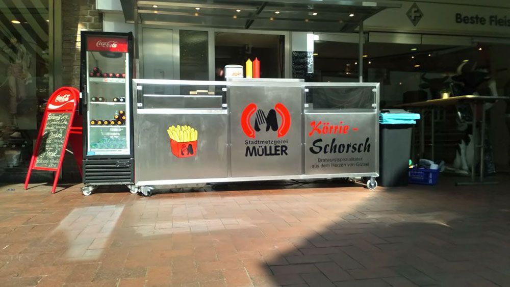 Vor einem Gebäude parkt ein Imbisswagen aus Edelstahl.
