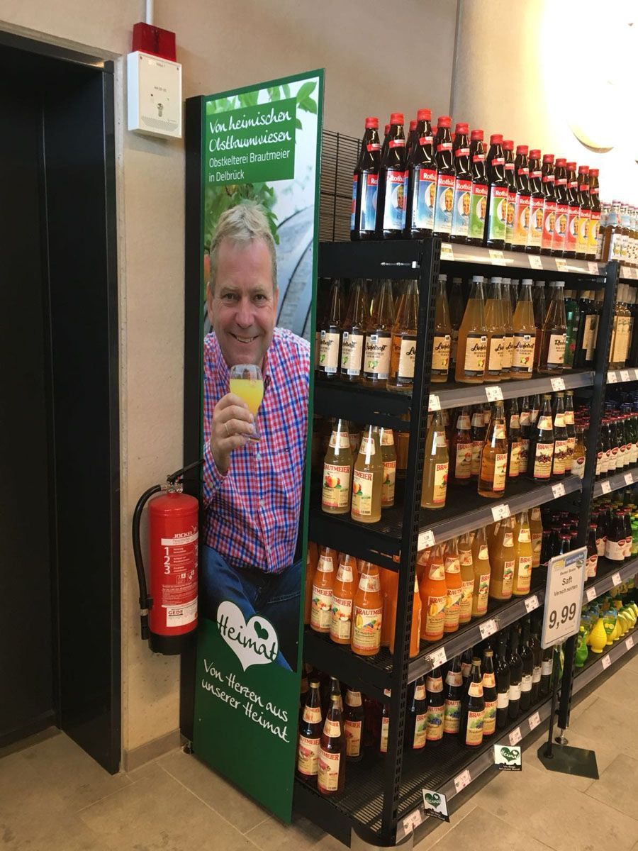 Ein Mann trinkt Orangensaft aus einem Kühlschrank in einem Geschäft.