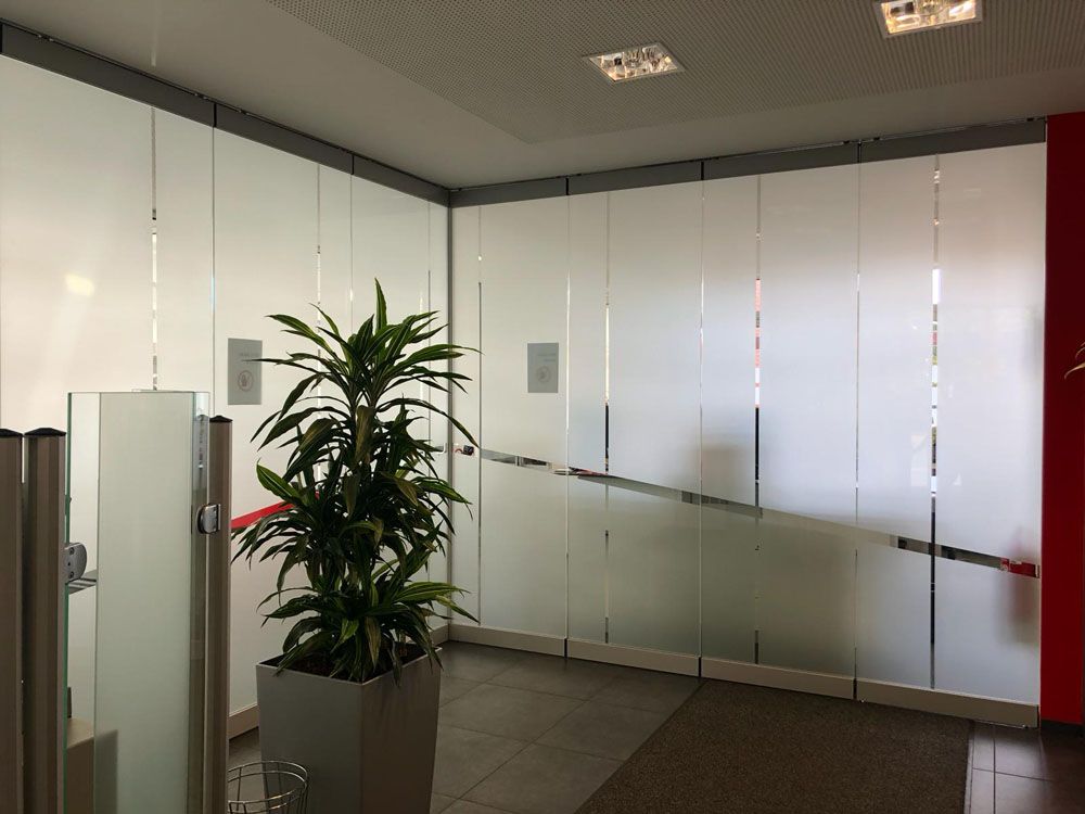 Ein Raum mit einer Pflanze in einem Topf vor einer Glaswand.