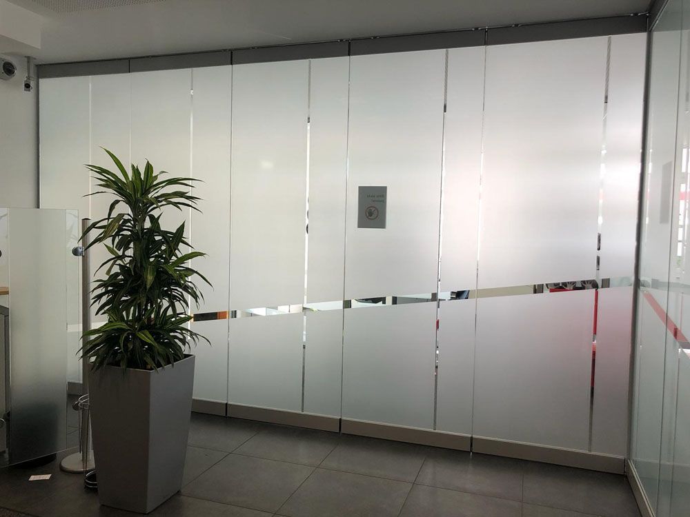 Eine Topfpflanze steht vor einer Glaswand.