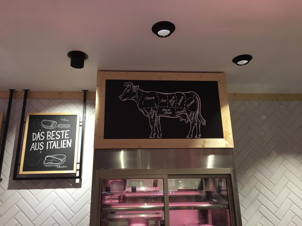 Über einem Schild mit der Aufschrift „Das Beste aus Italien“ hängt ein Bild einer Kuh.
