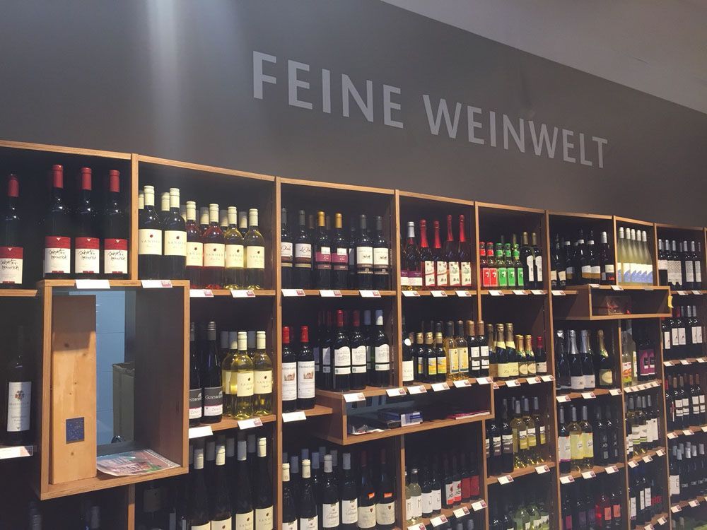 Ein Regal voller Weinflaschen mit einem Schild mit der Aufschrift „feine weinwelt“