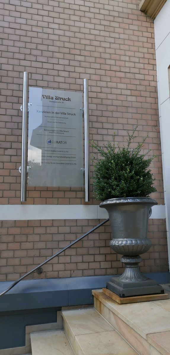 Eine Topfpflanze steht auf den Stufen eines Gebäudes neben einer Backsteinmauer.