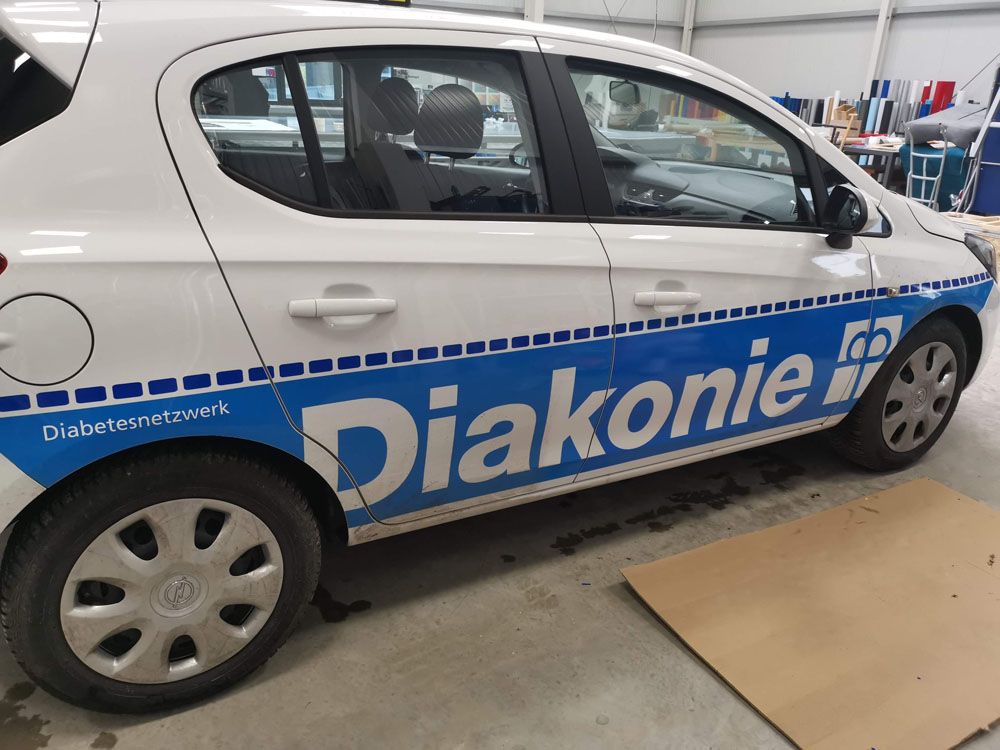 Ein weiß-blaues Auto mit dem Wort Diakonie darauf