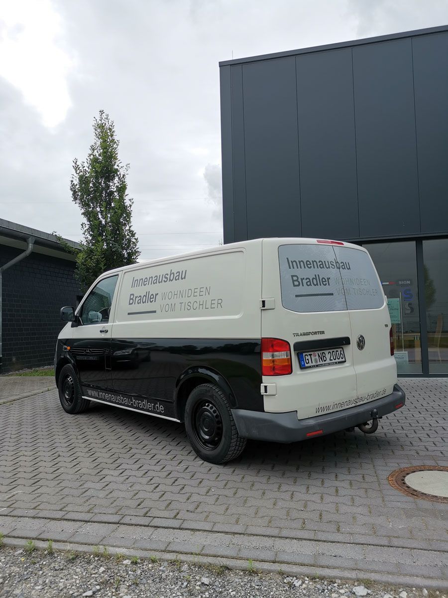 Ein schwarz - weißer Lieferwagen ist vor einem Gebäude geparkt.