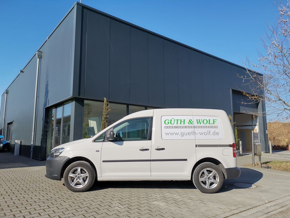 Ein weißer Lieferwagen steht vor einem Gebäude.