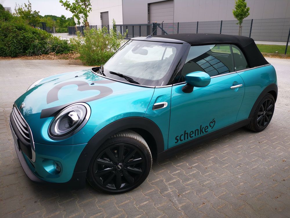 Ein blauer Mini Cooper mit dem Wort Schenke auf der Seite