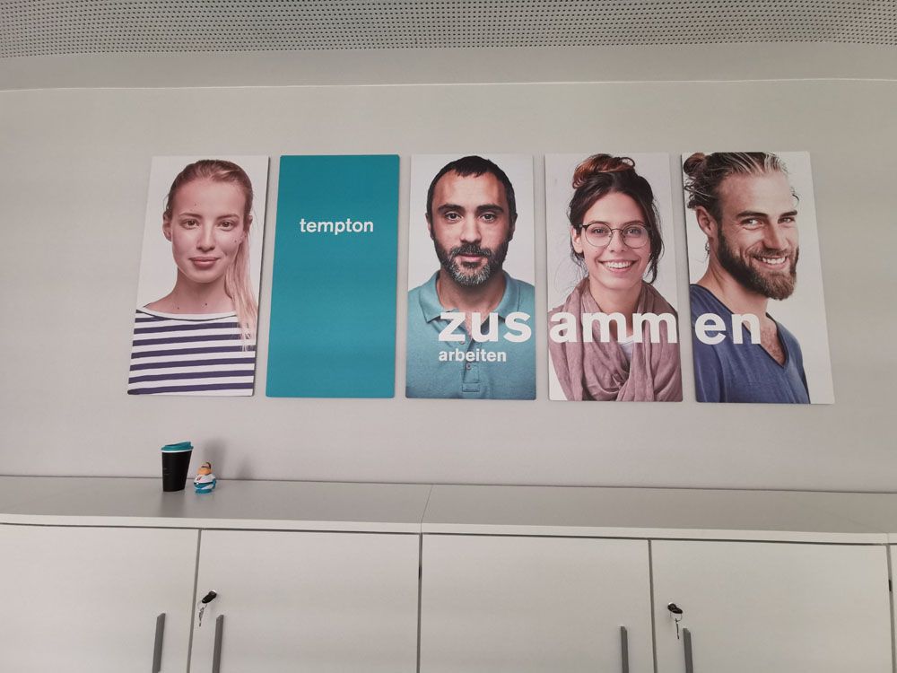 An einer Wand hängen vier Porträts von Menschen.