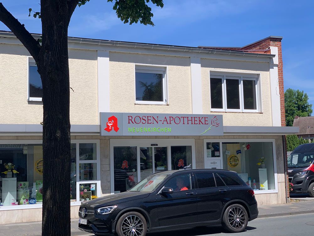 Ein schwarzes Auto steht vor einem Geschäft namens Rosen-Apotheke