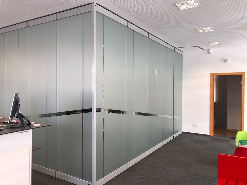 Ein Raum mit einer Glaswand und einem Computer auf einem Schreibtisch.