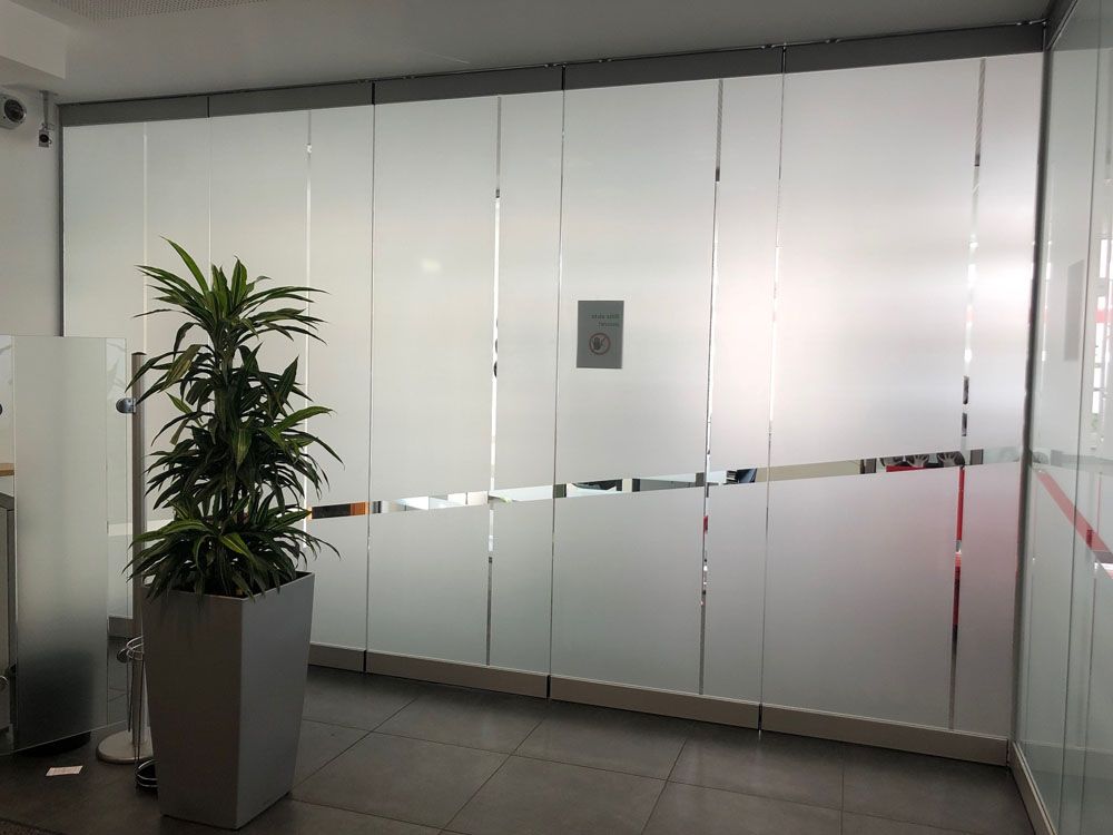 Eine Topfpflanze steht vor einer Glaswand.