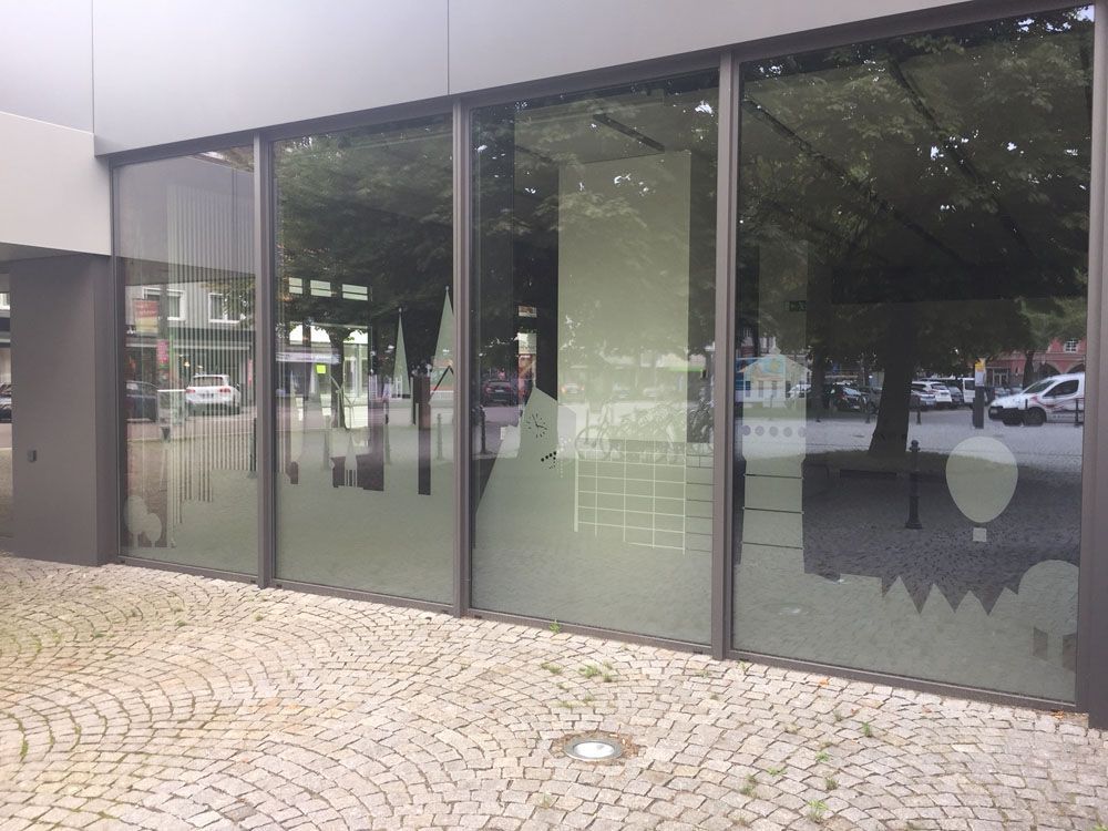 Ein Gebäude mit vielen Fenstern und einem gemauerten Gehweg davor.