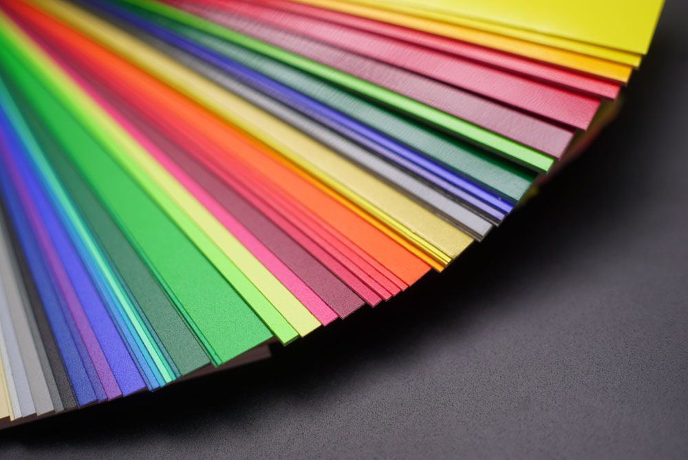 Eine Nahaufnahme eines Fächers aus verschiedenfarbigen Papieren auf einem Tisch.