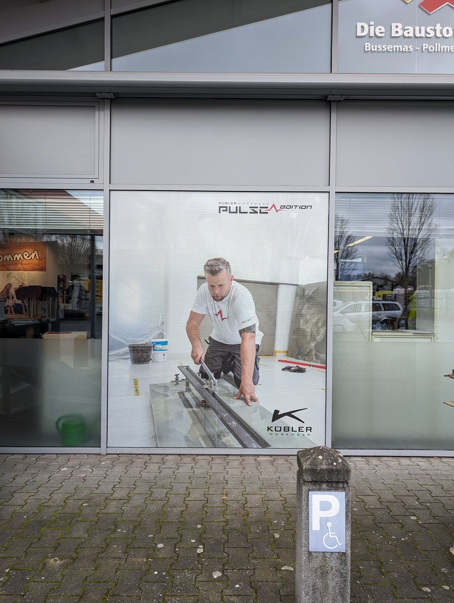 Ein Mann schneidet ein Stück Holz aus dem Fenster eines Gebäudes.
