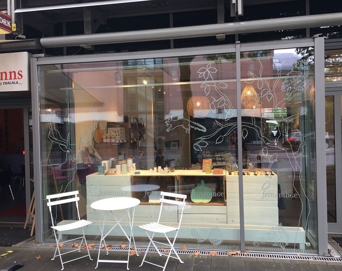 Eine Ladenfront mit Tischen und Stühlen davor.