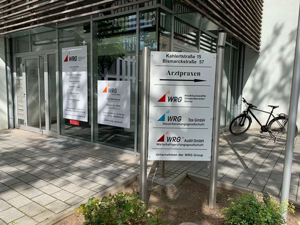 Vor einem Gebäude steht ein Fahrrad, davor ein Schild.