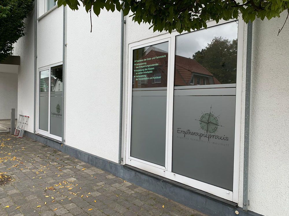 Ein weißes Gebäude mit vielen Fenstern und einem Baum davor.