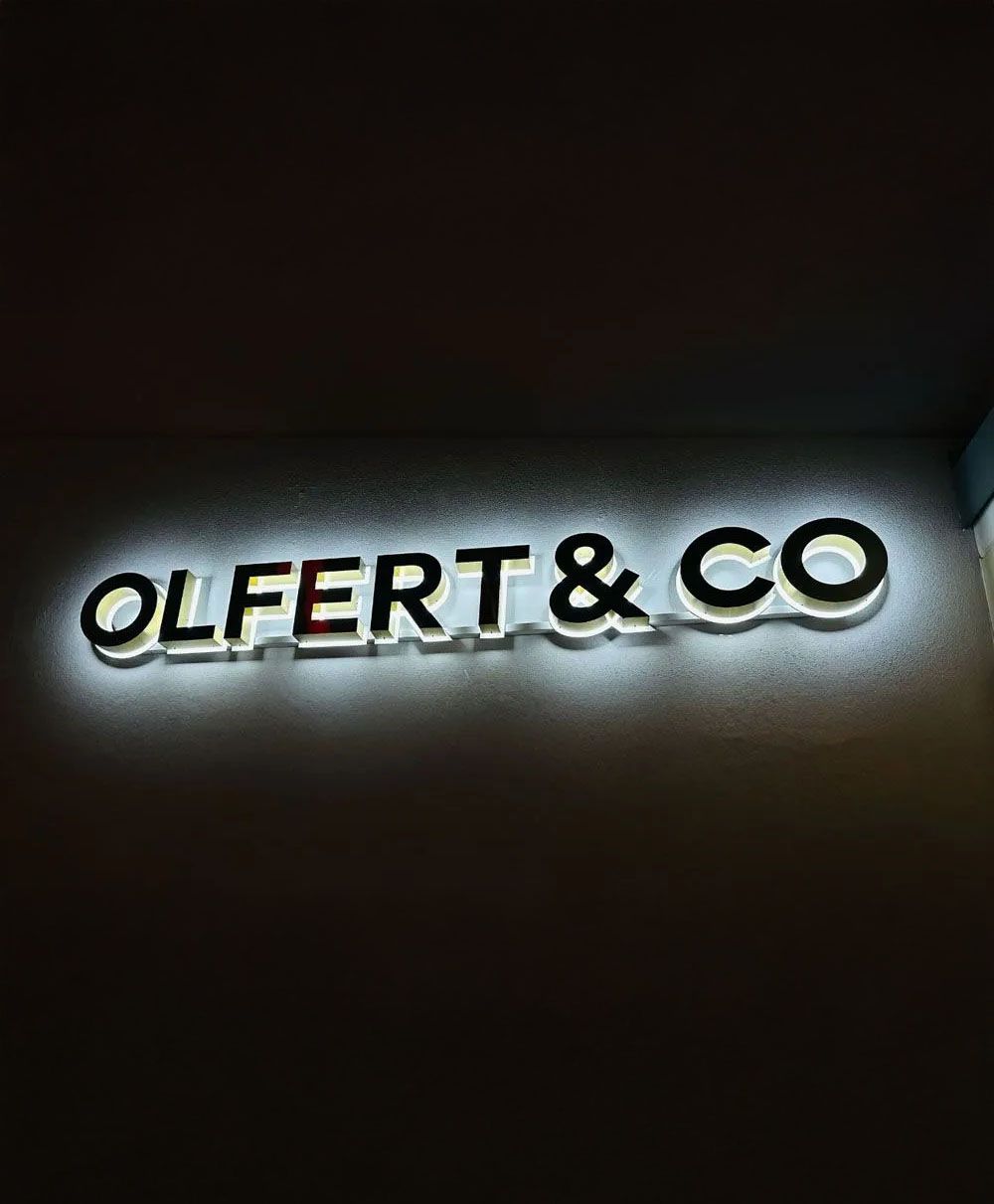 Ein Schild mit der Aufschrift „Olfert & Co.“ ist nachts beleuchtet.