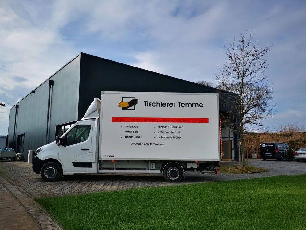 Ein weißer Lastwagen steht vor einem Gebäude.