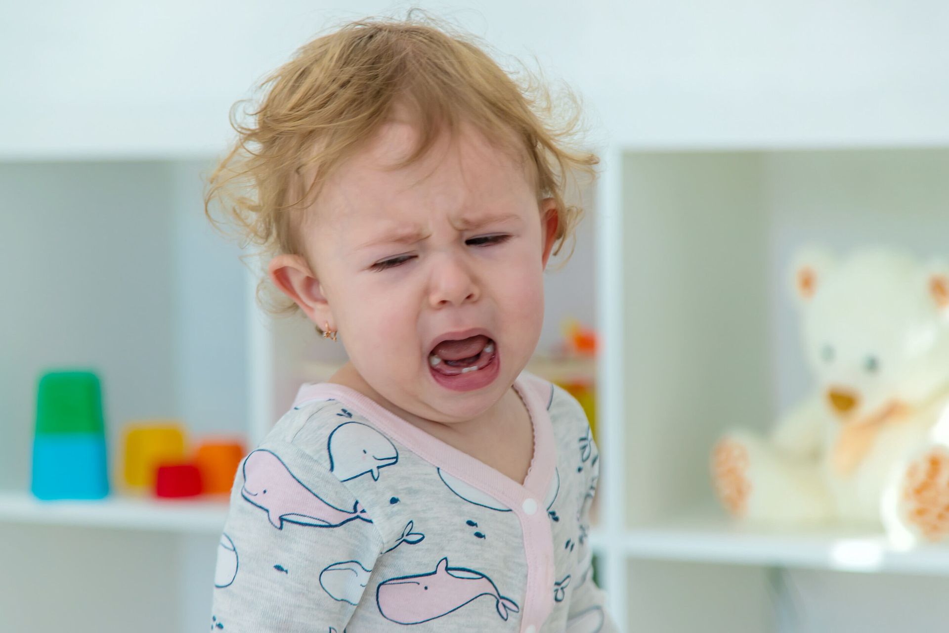 Una niña está llorando en una habitación con juguetes.