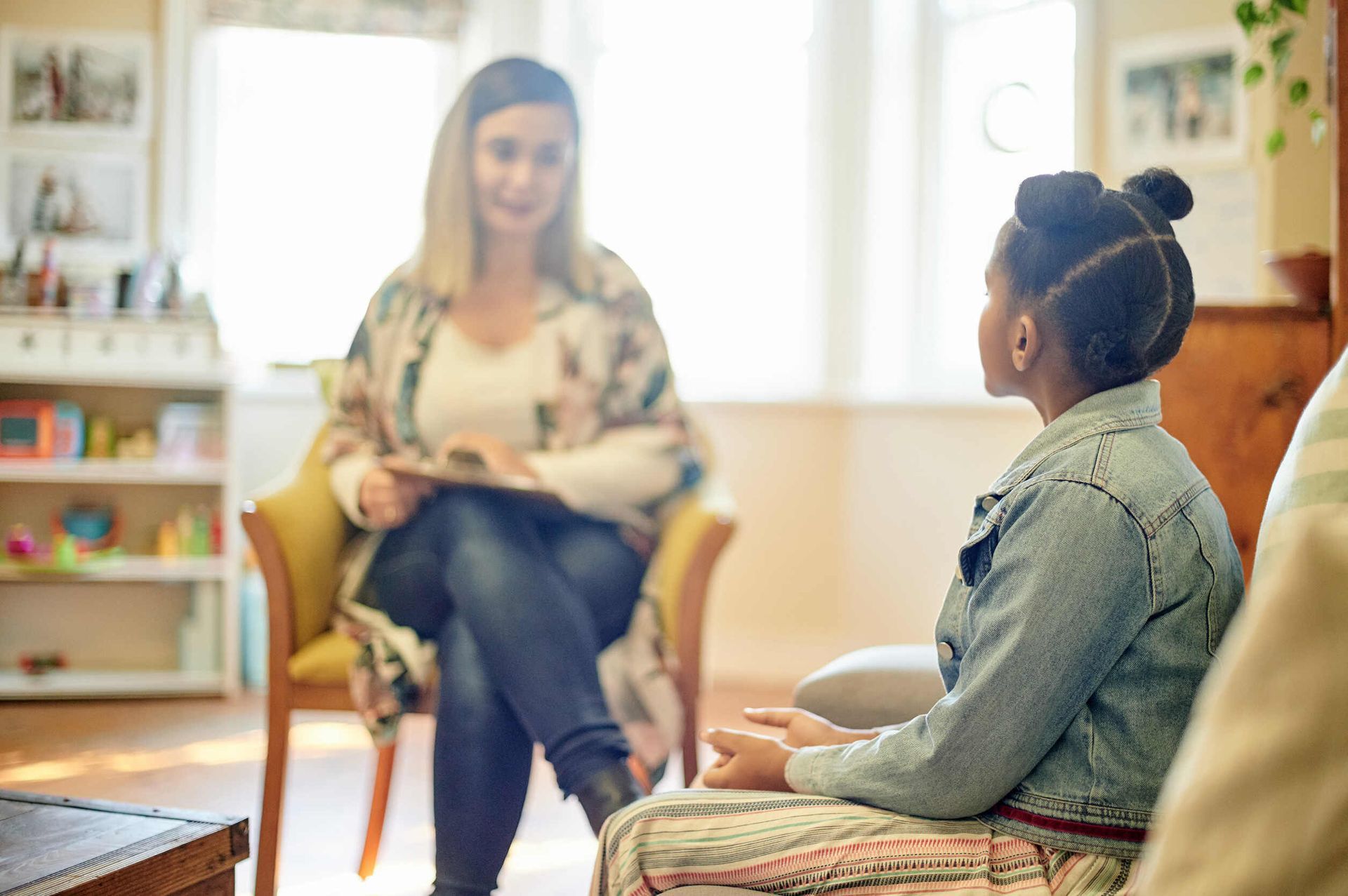 Una mujer está sentada en un sofá hablando con otra mujer en una sala de estar.