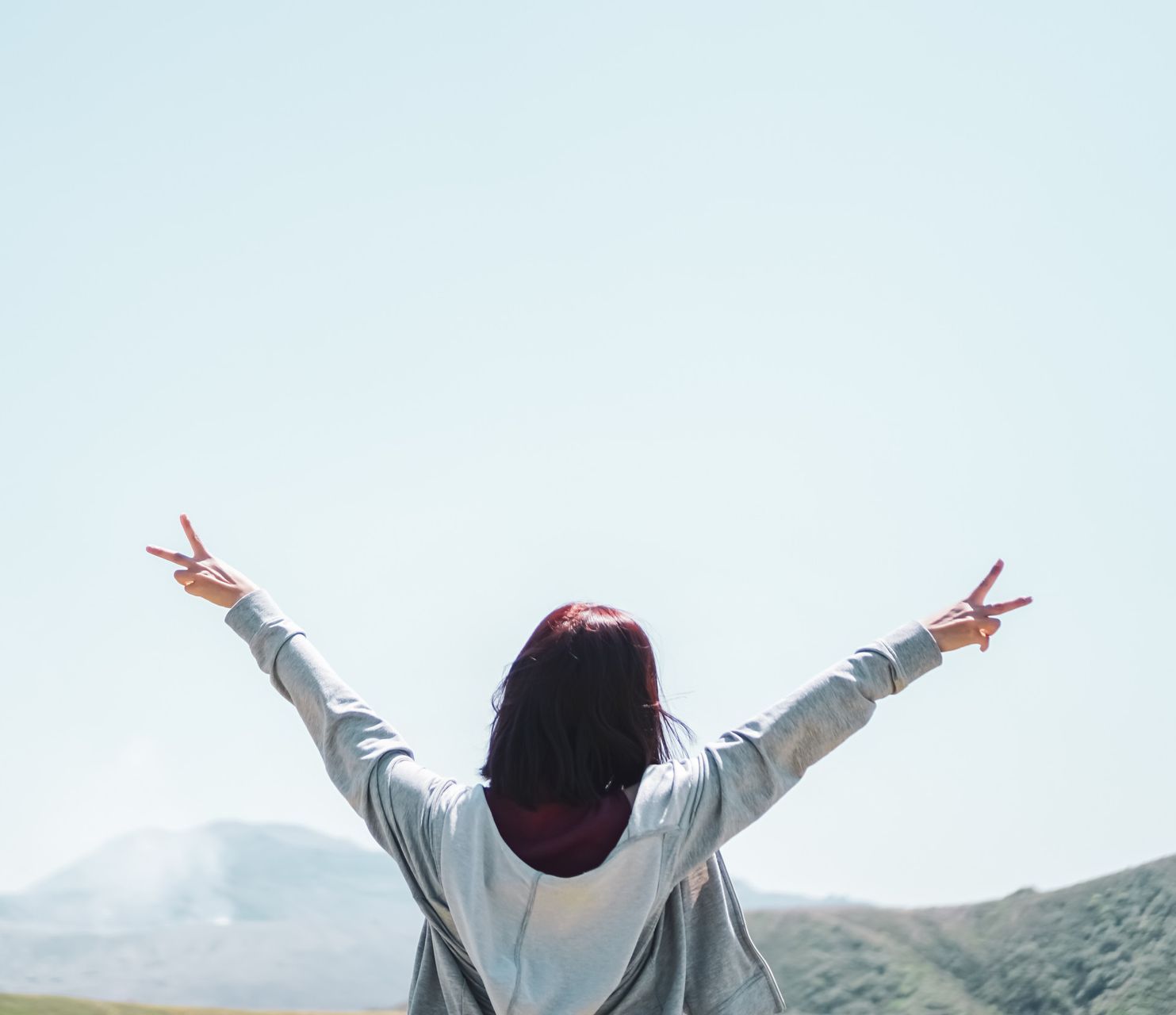 Una mujer está de pie con los brazos extendidos y haciendo un signo de paz.