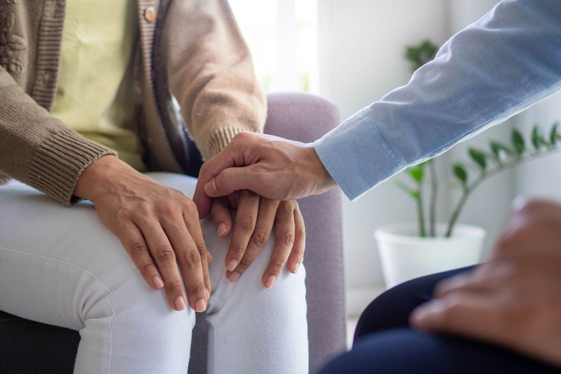 Un hombre sostiene la mano de una mujer mientras está sentado en un sofá.