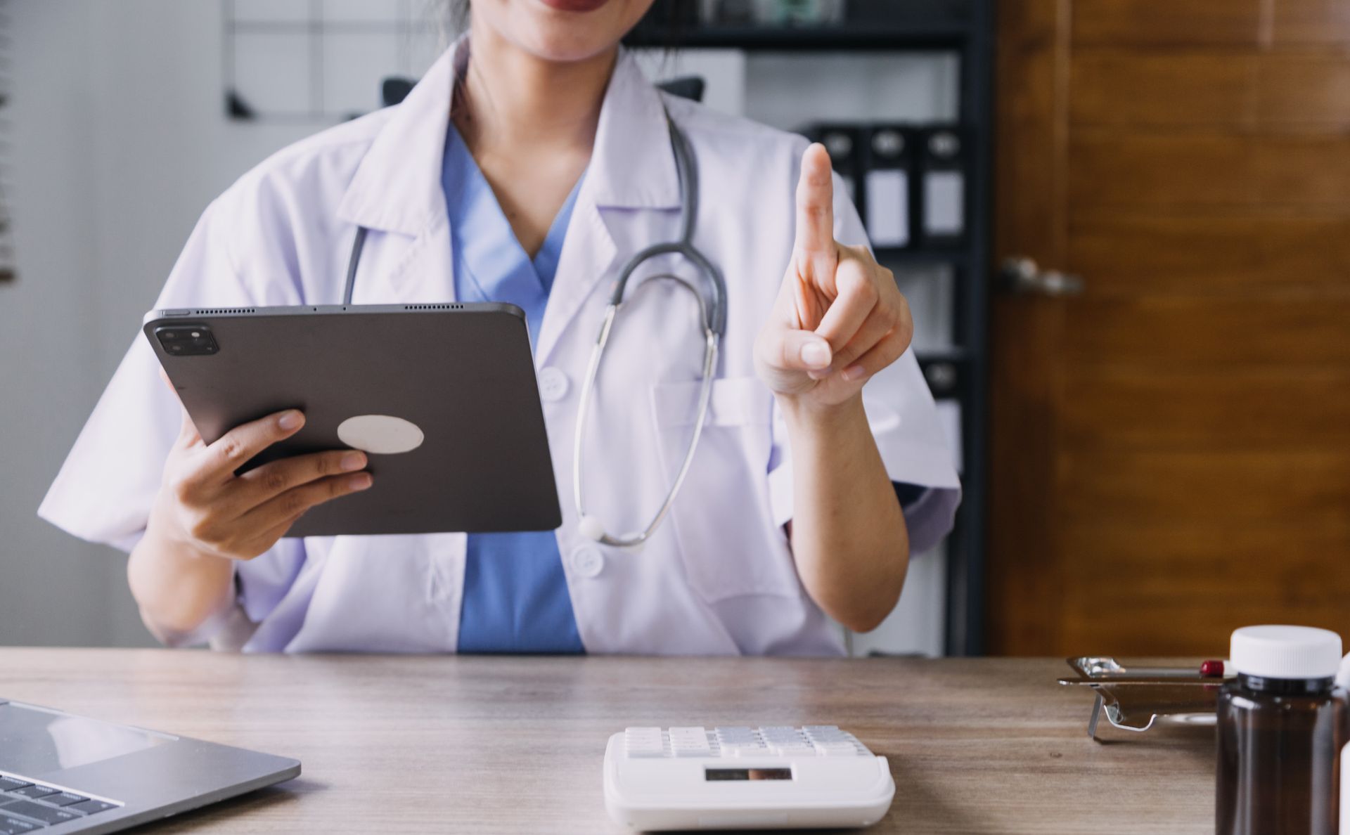 Una doctora está sentada en un escritorio usando una tableta.