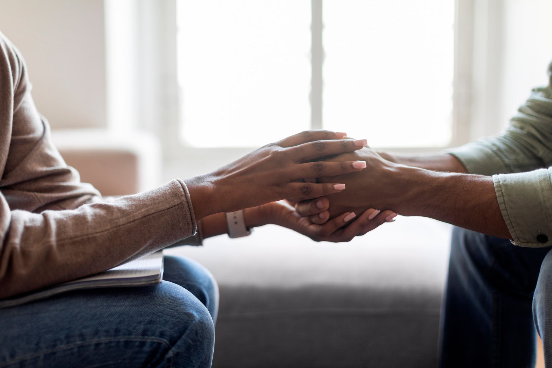 Un hombre y una mujer se toman de la mano mientras están sentados en un sofá.