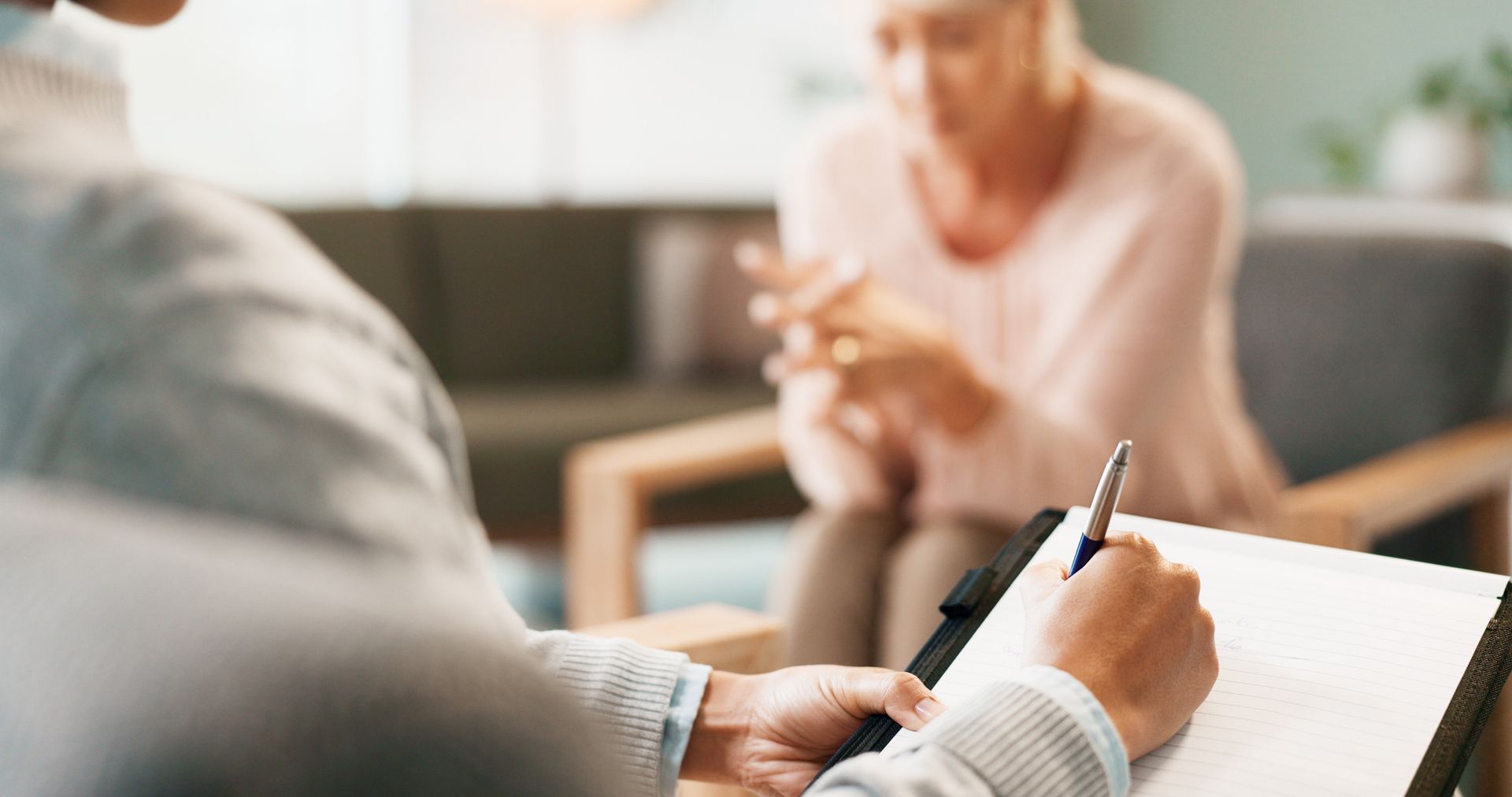 Un hombre está escribiendo en un portapapeles mientras una mujer está sentada en una silla.