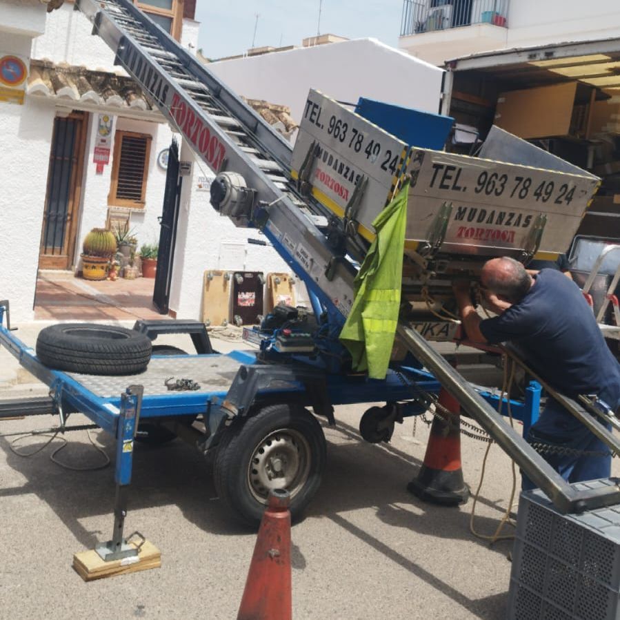 Un hombre está trabajando en un remolque con un cartel que dice tel 963 78 49 24