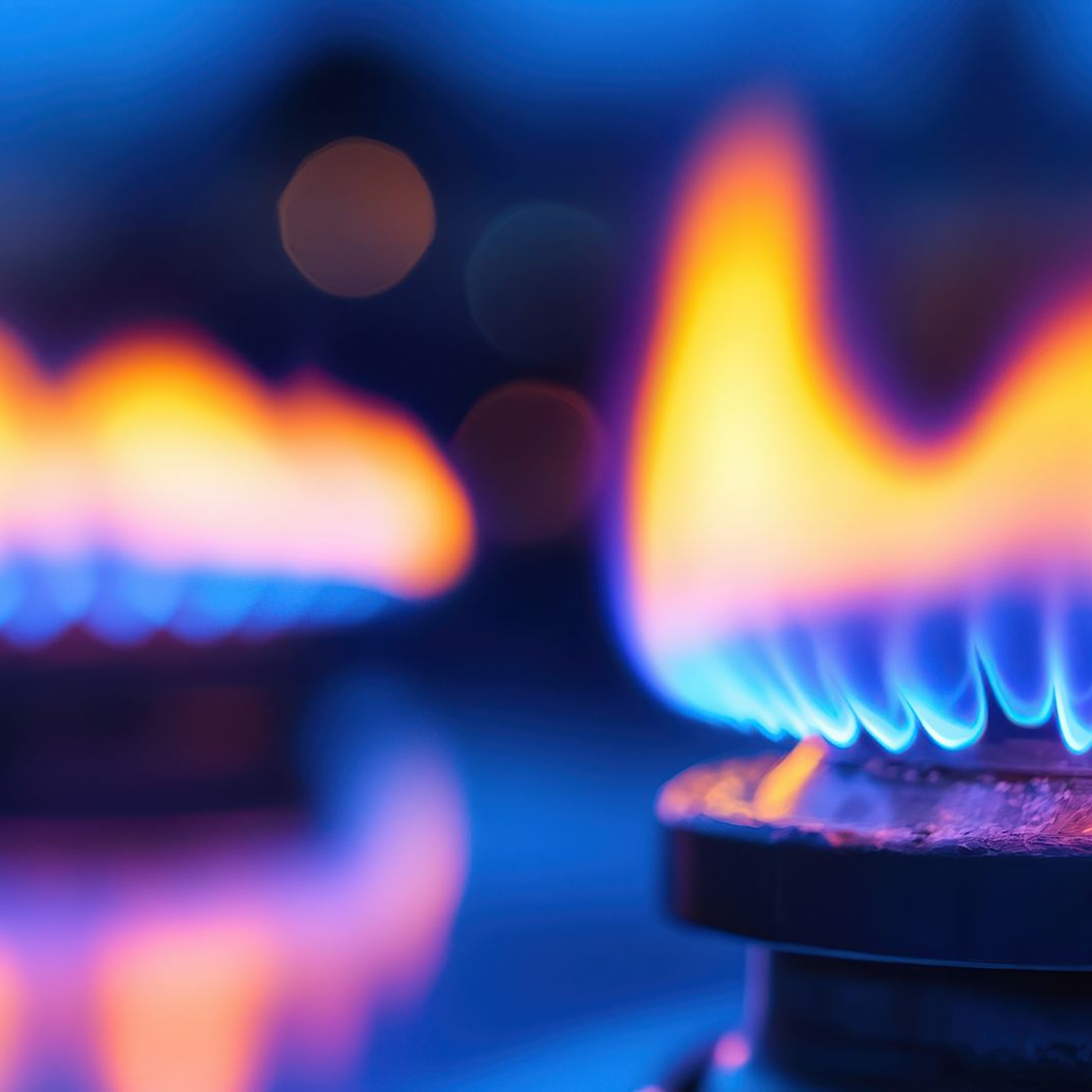Flammes aux teintes bleues et orangées provenant d'un brûleur de cuisinière à gaz.
