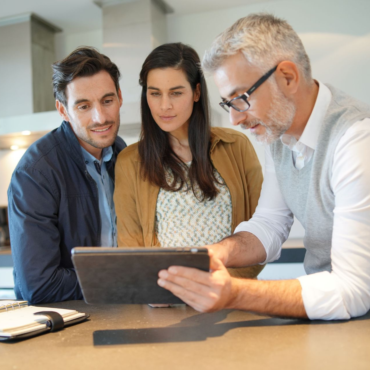 Un couple regarde une tablette avec un homme.