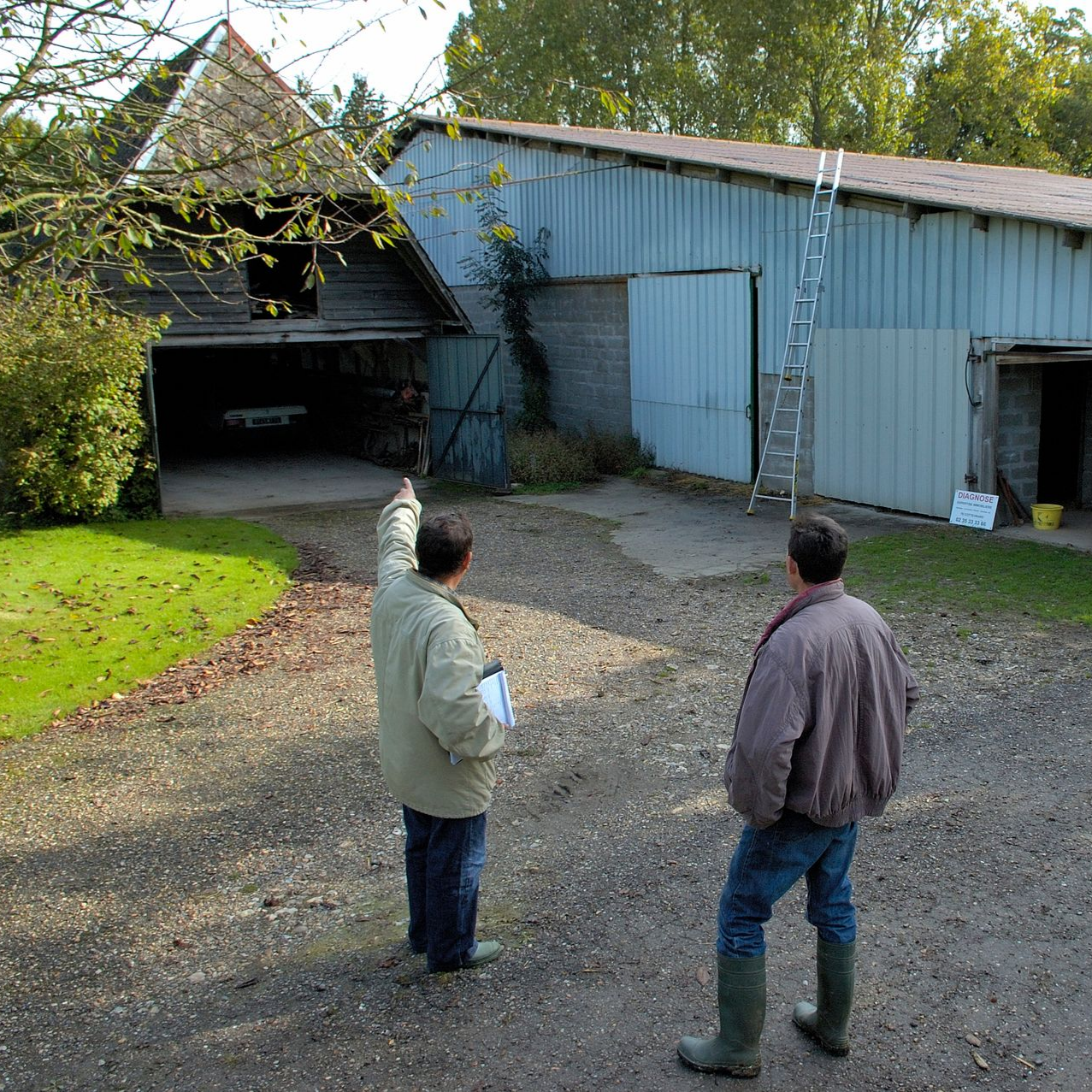 Deux hommes près de bâtiments agricoles.