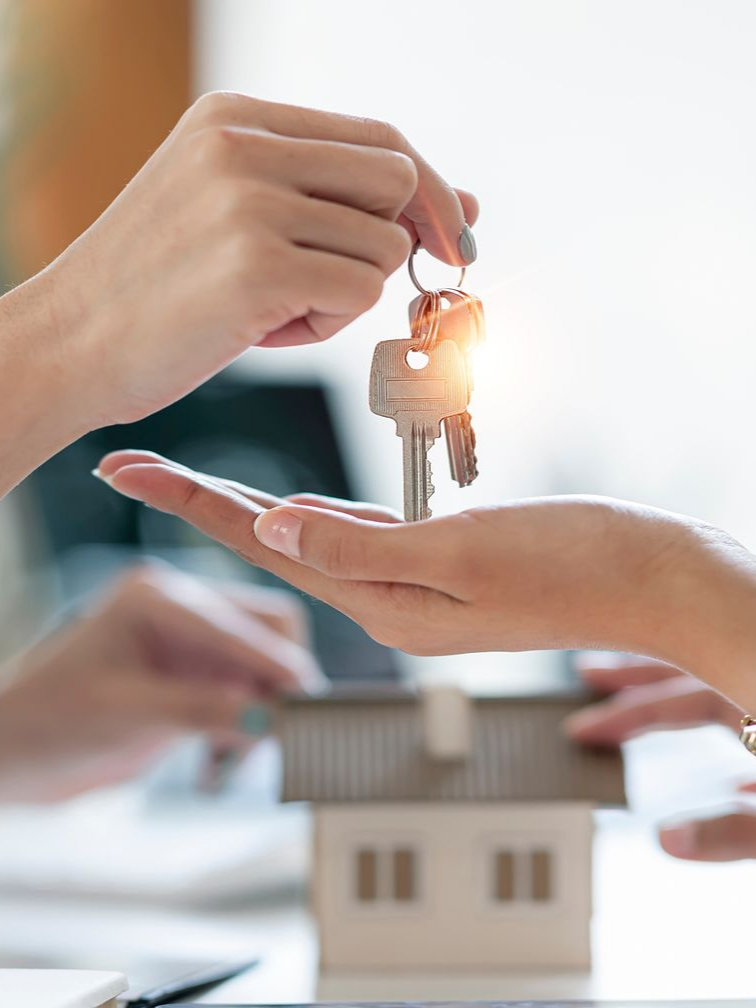 Une main remet les clés d'une maison.