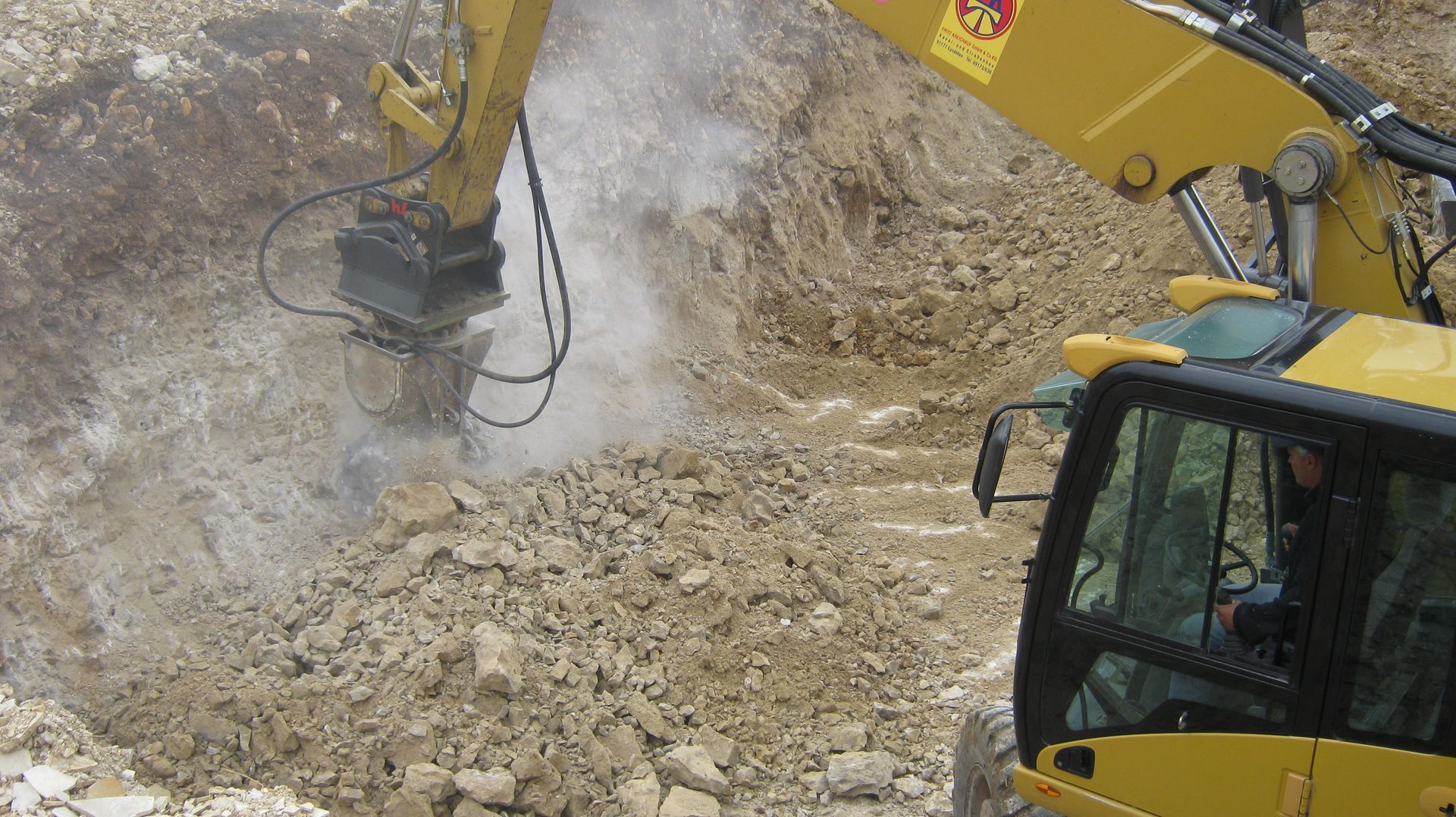 Gelber Bagger steht inmitten einer Baugrube