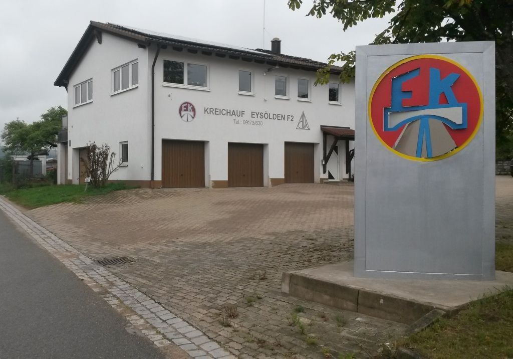Einfahrt Büro von FK Weißes Haus und ein Metallschild mit dem FK Logo darauf