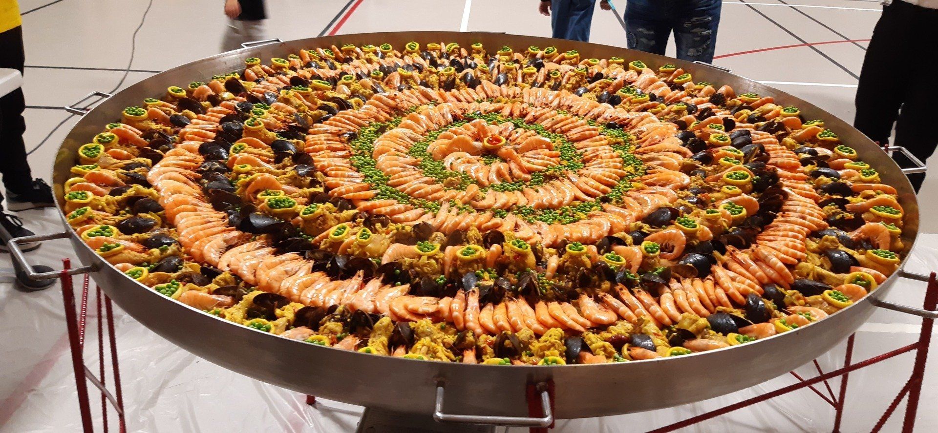 Plateau de paella rangées de crevettes et petits pois.