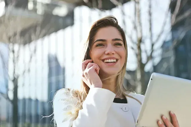 Una mujer habla por teléfono celular mientras sostiene una tableta.