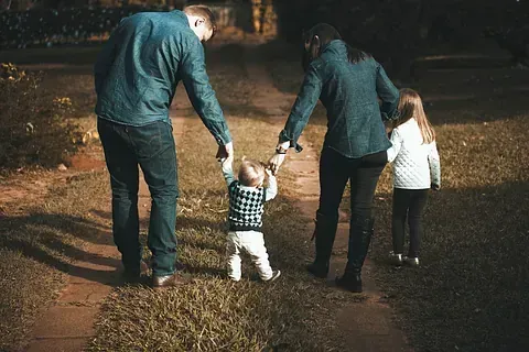 Una familia camina por un sendero tomados de la mano.