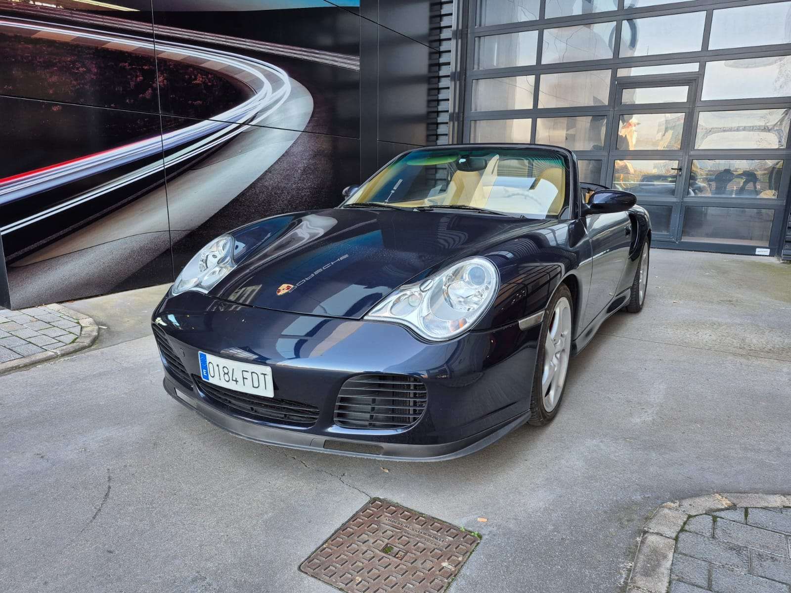 Un Porsche 911 Cabriolet negro está estacionado frente a un edificio.