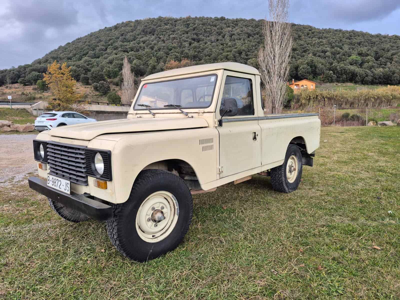 Un camión blanco está estacionado en un campo de hierba con una montaña al fondo.