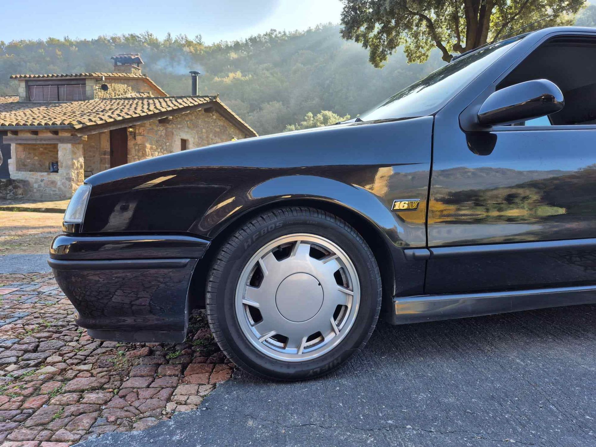 Un coche negro está aparcado al costado de la carretera.